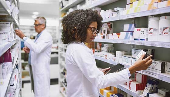 Two pharmacists looking at the medications on the shelves