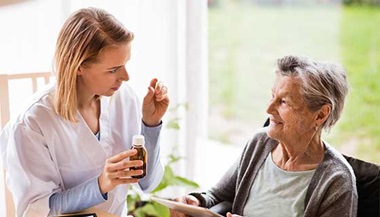 doctor talking to older lady holding medicine