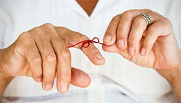 Man with a red string tied around his finger to help remember