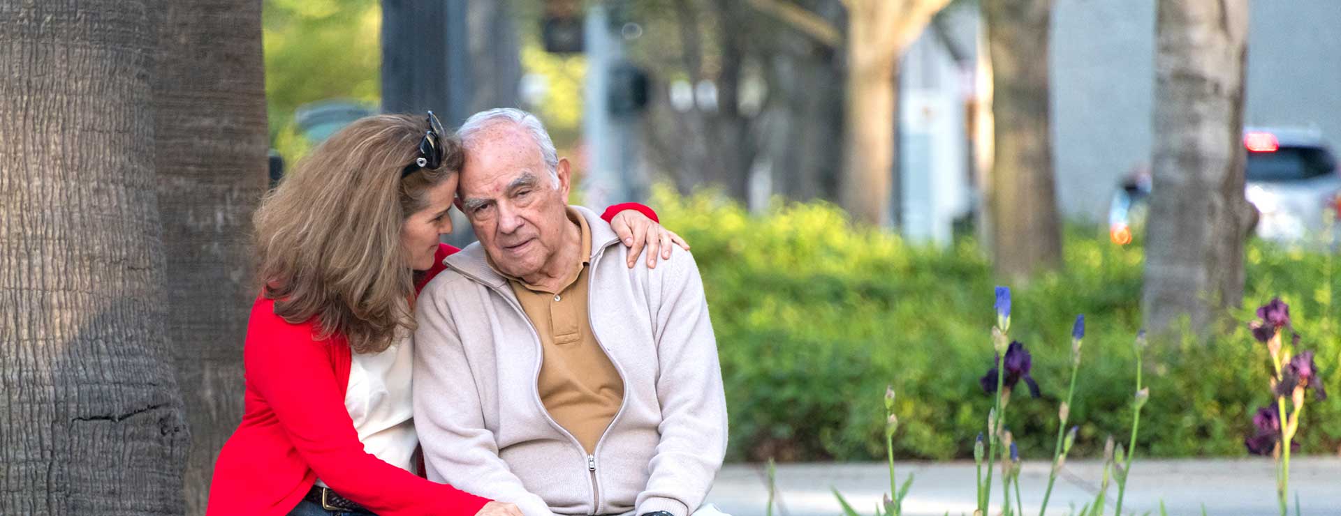 Daughter talking to a senior father on a park bench