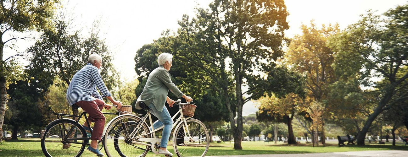 An older couple biking in a park