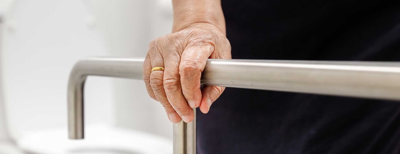 Older woman holding onto a rail