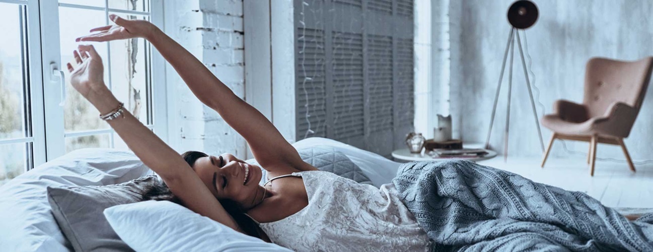 A woman stretching in bed in the morning