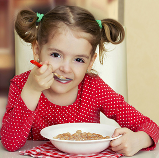 Three year old girl eating breakfast at a table.