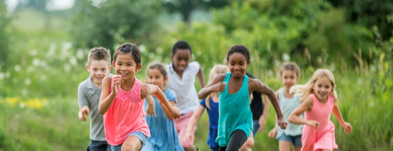 A diverse group of young children running in the grass