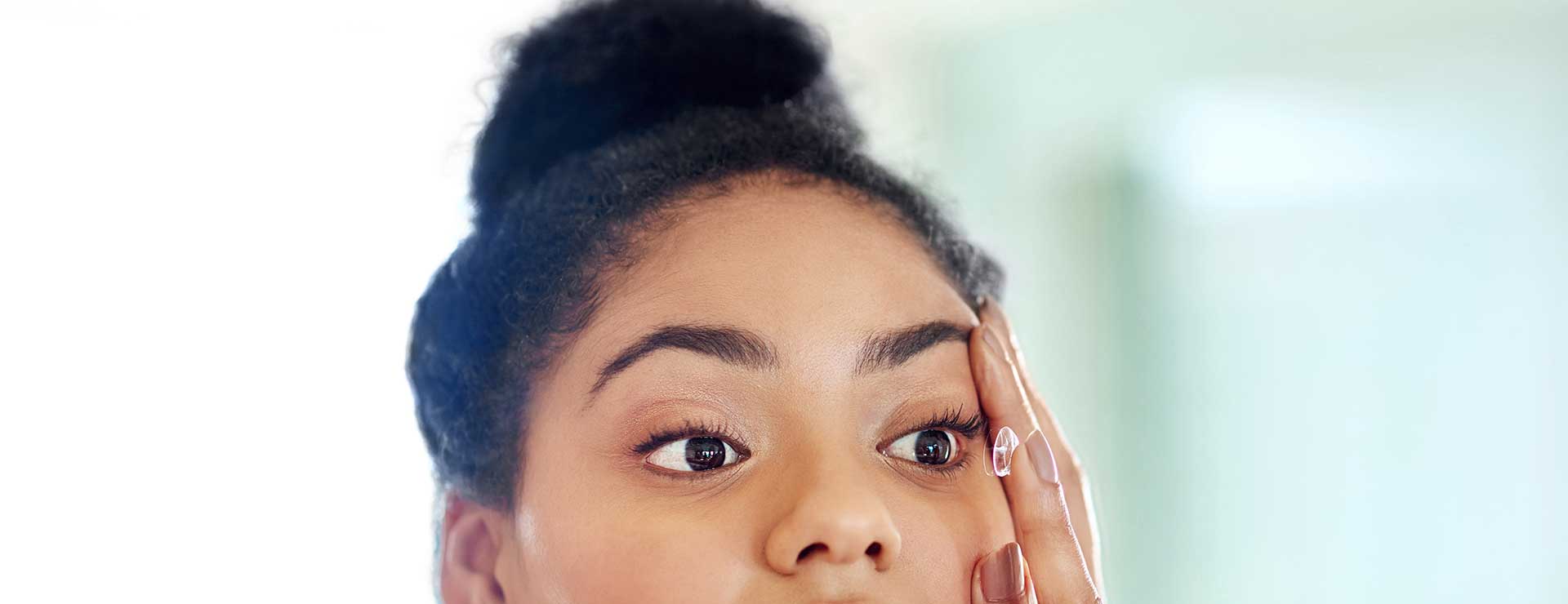 a young woman inserting a contact lens