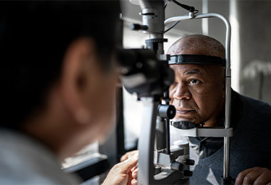 A man sits for an eye exam with a physician.