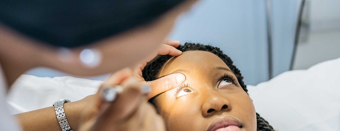 a doctor shines a light into eye of female patient