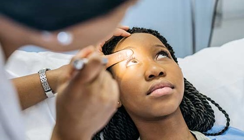 a doctor shines a light into eye of female patient