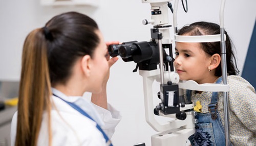 A doctor observes the eye of the child with a slit lamp