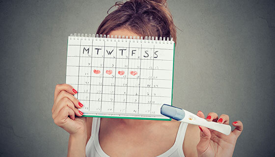 woman holds calendar and pregnancy test
