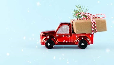 A small toy truck with a small wrapped gift in the back bed.