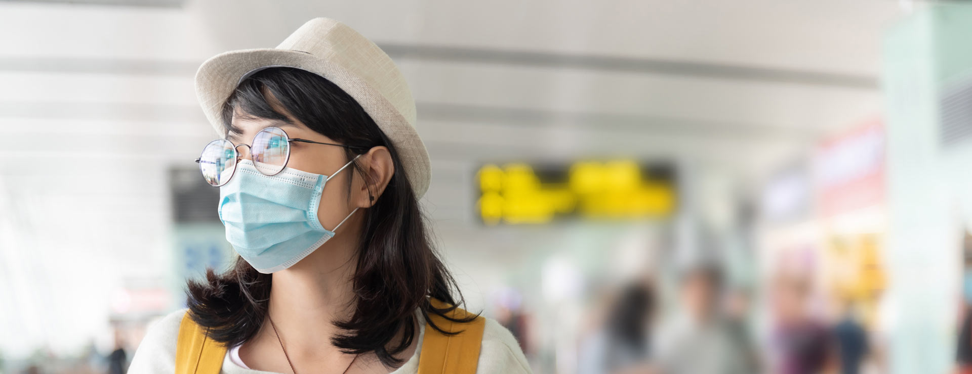 Traveler wearing a mask for safety in a busy and crowded airport