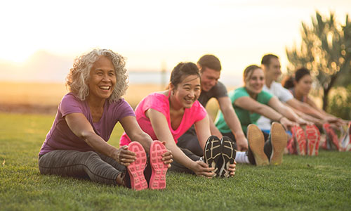 A group of smiling adults stretch before exercising.