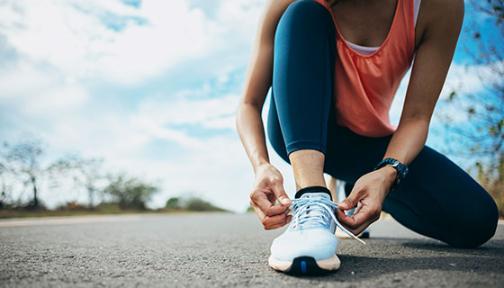 Woman laces her running shoes on a sunny morning