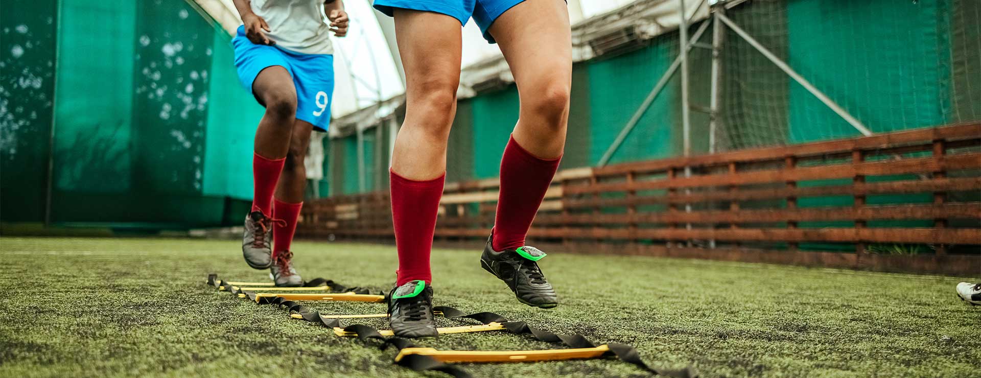 Soccer players warming up on the field, using a rope ladder.