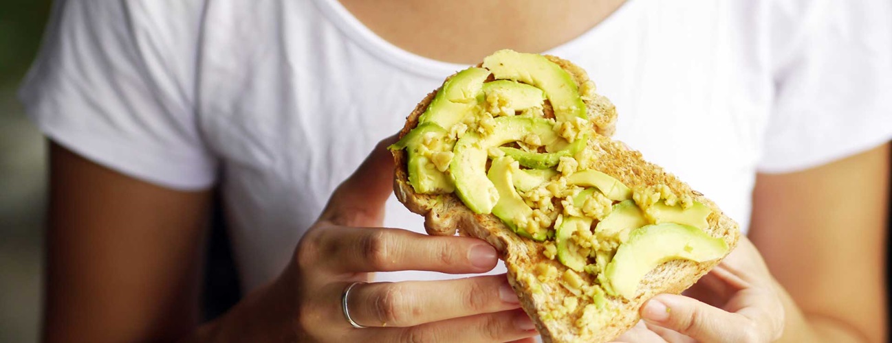 Closeup of woman holding avocado toast