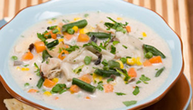 A bowl of healthy chicken and dumpling soup with vegetables