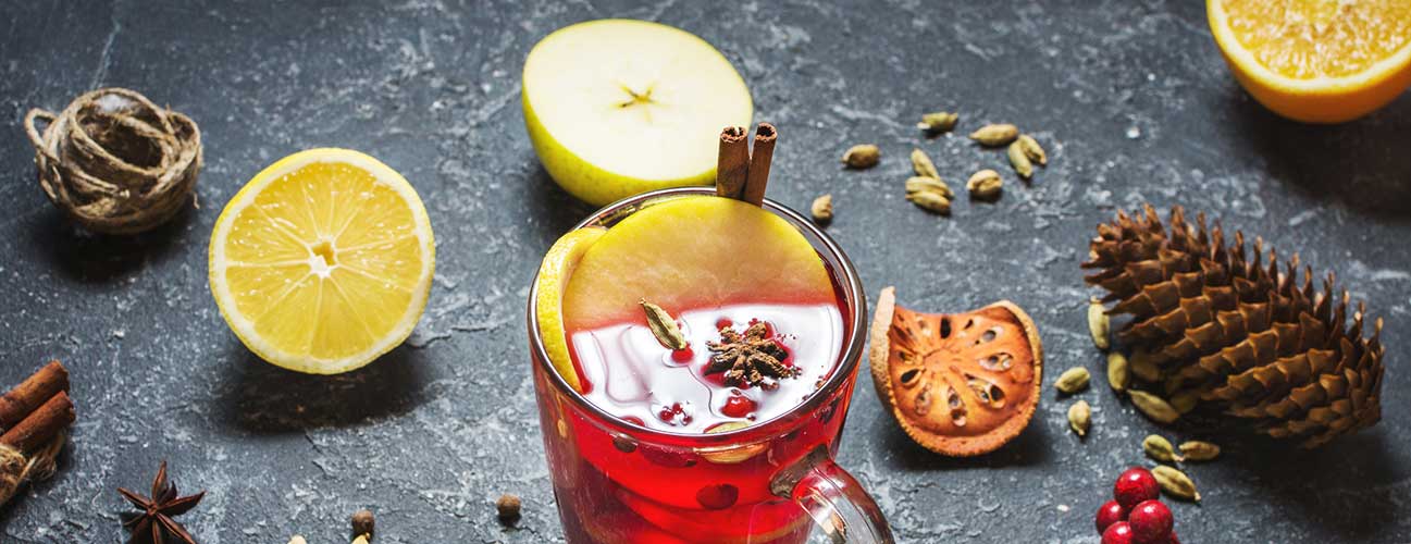 Cider glass surrounded by citrus peels and various spices