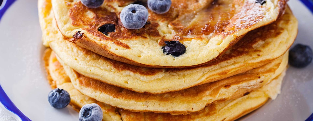 A plate of pancakes with blueberries on top.