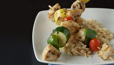 Plate of healthy Greek kabobs with tomato, zucchini, and chicken