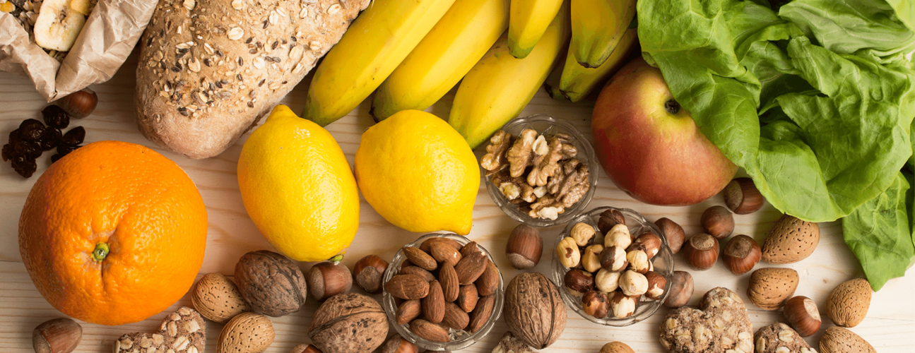 medley of high fiber foods including oranges, bananas, nuts, lettuce, lemons and bread.
