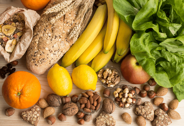 medley of high fiber foods including oranges, bananas, nuts, lettuce, lemons and bread.