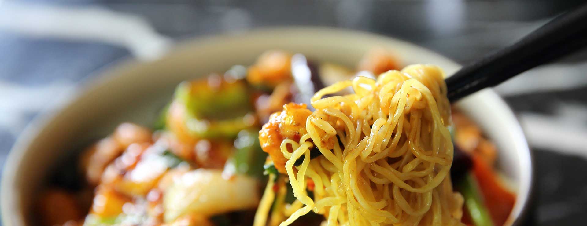 Eating a bowl of noodles with chopsticks.