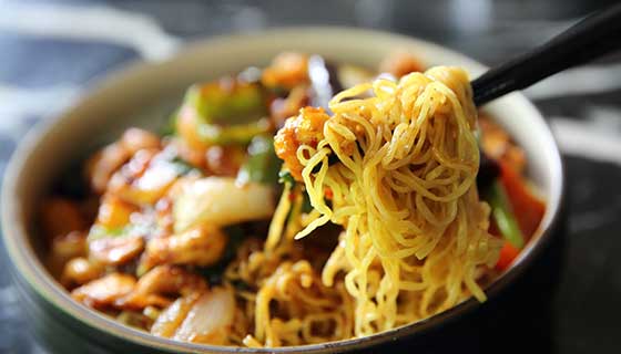 Eating a bowl of noodles with chopsticks.