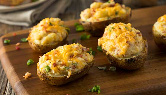 Four baked potatoes on a cutting board.