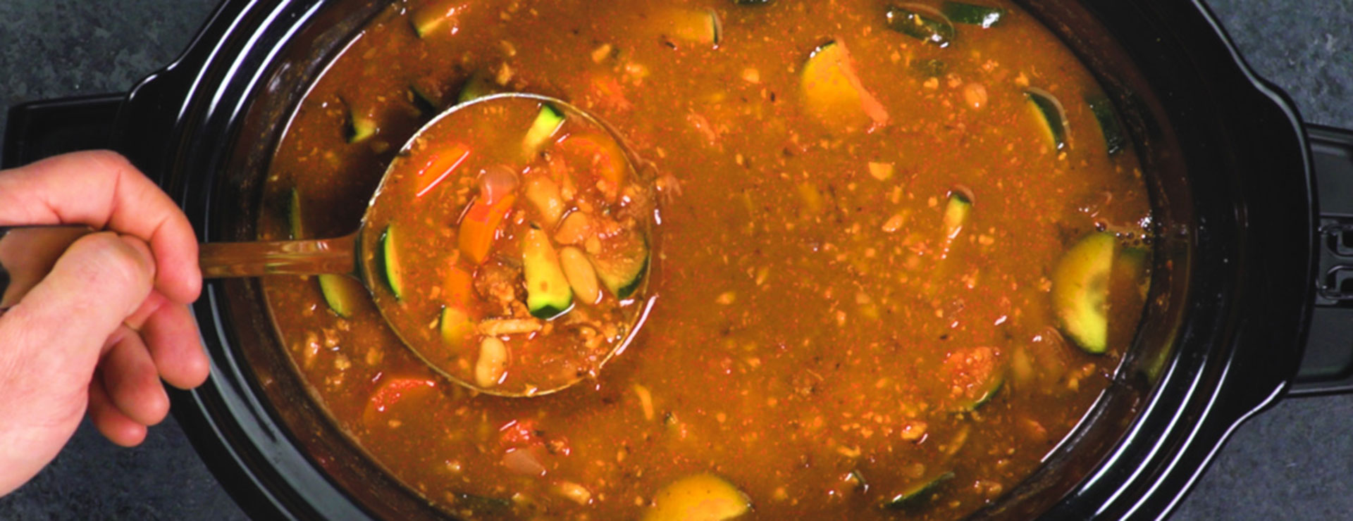 a person ladling turkey vegetable soup
