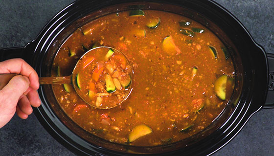 a person ladling turkey vegetable soup