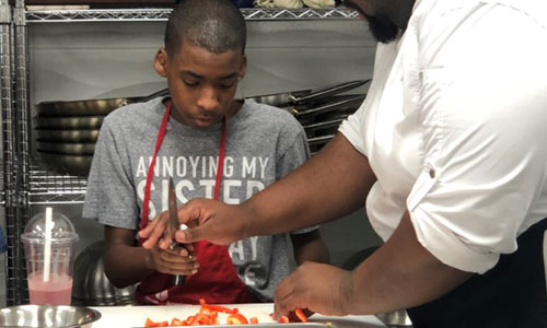 a child chops peppers in a cooking class