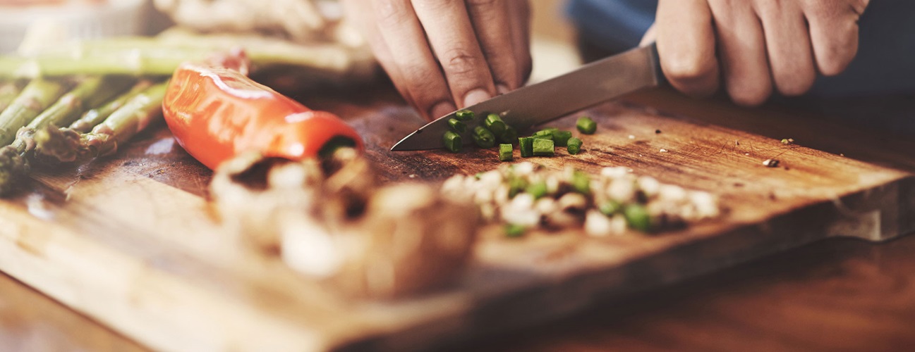 a closeup of a man's hands chopping vegetables