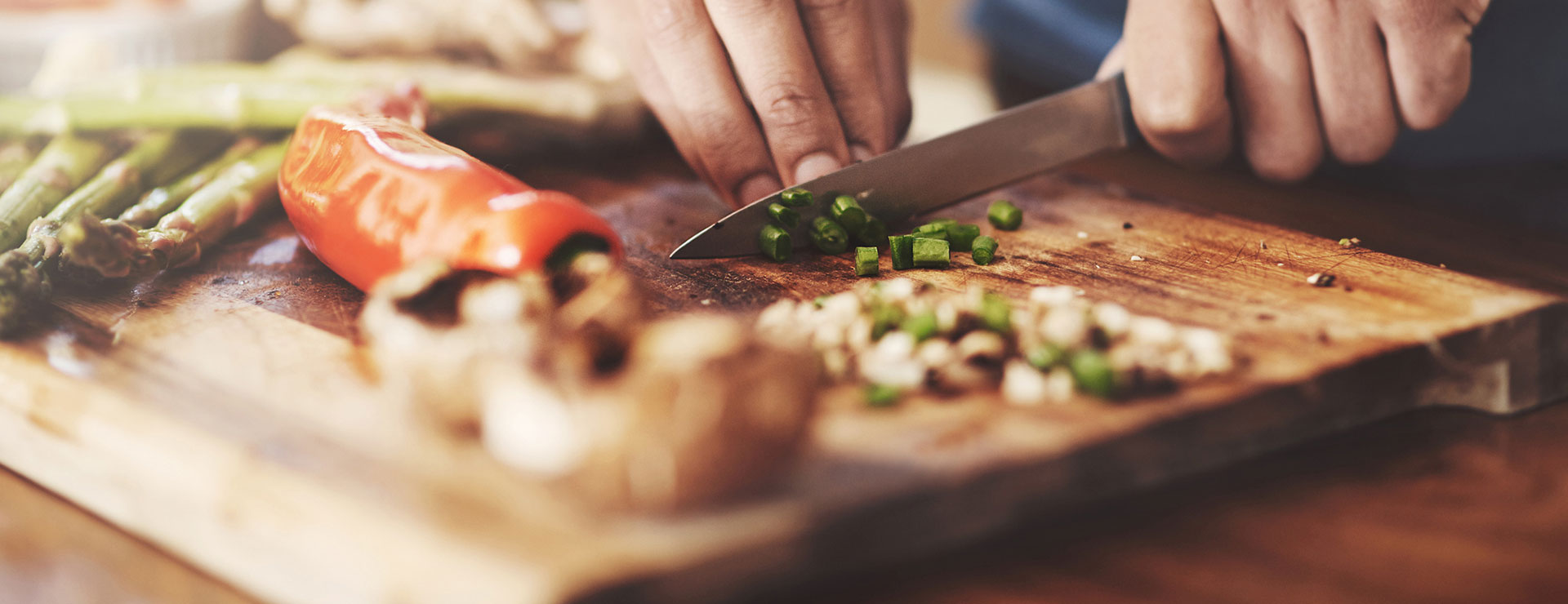 a closeup of a man's hands chopping vegetables