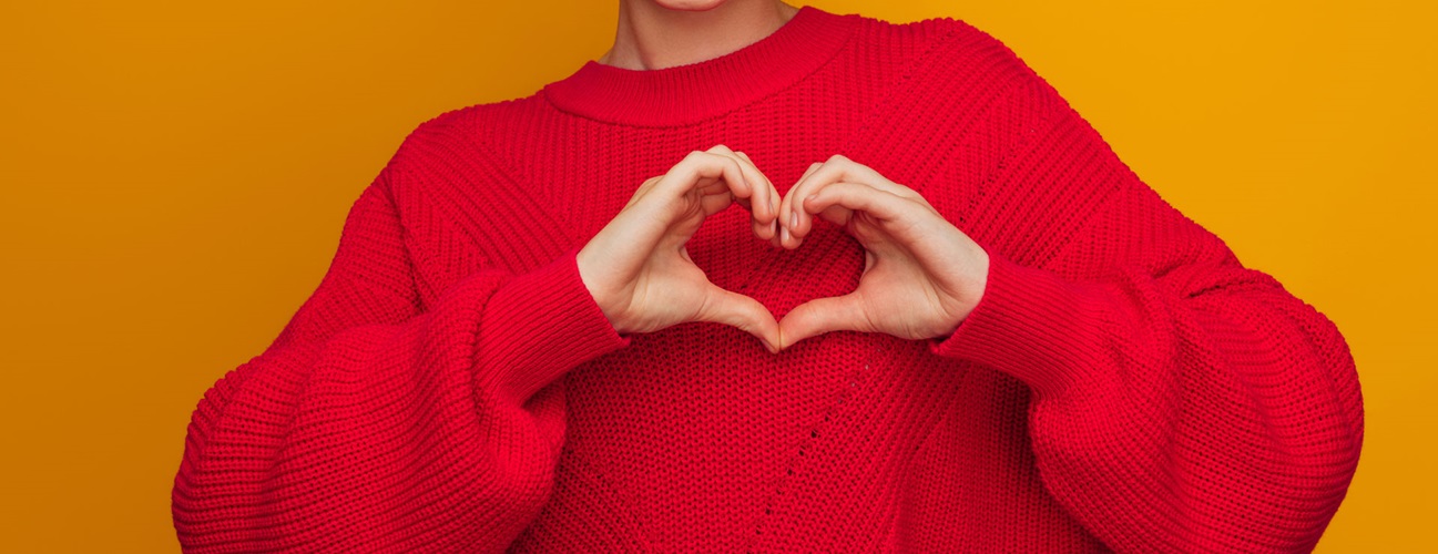 a woman in a red sweater makes a heart with her hands