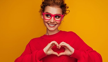 a woman in a red sweater makes a heart with her hands