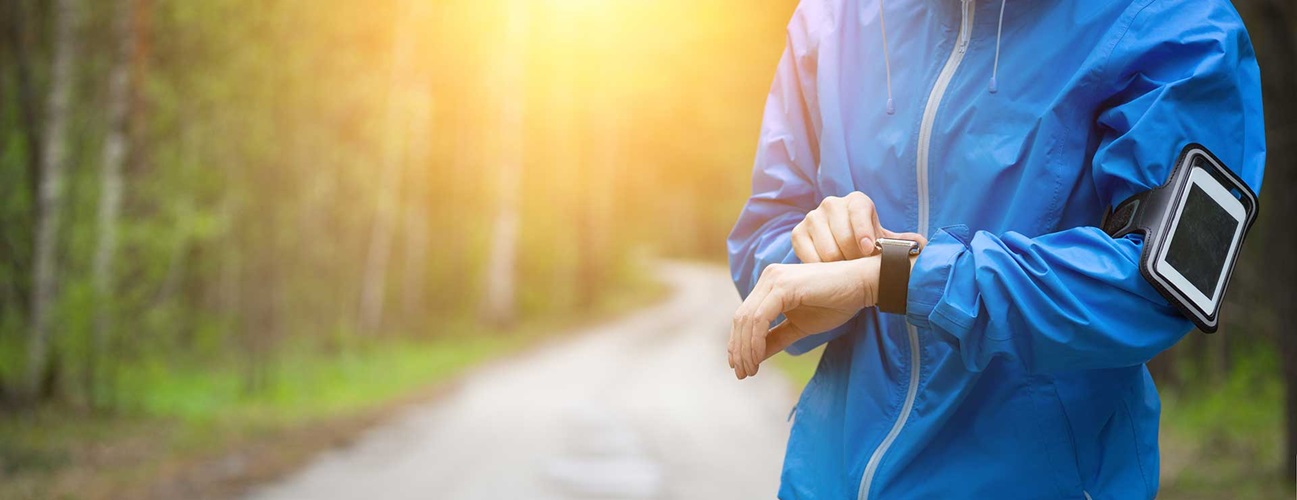 Woman on a running trail checks fitness tracker