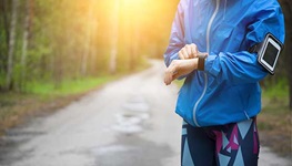 runnner checking fitness tracker along path