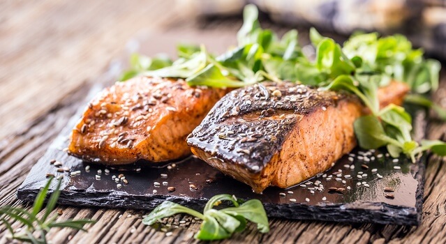 Two fillets of grilled salmon with argula.