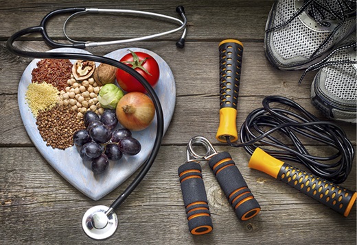 An arrangement of healthy foods on a heart-shaped plate surrounded by exercise equipment