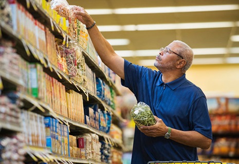 A man reaches for the top shelf in a grocery store