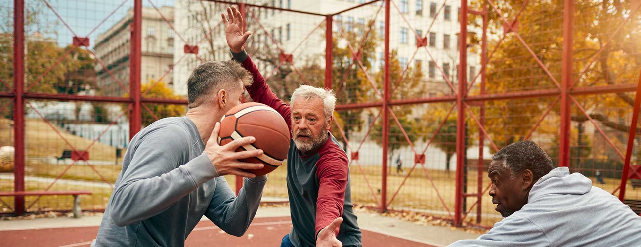 A group of seniors play basketball outdoors