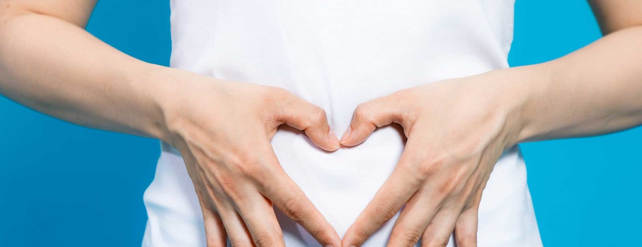 A woman making a heart with her hands over her stomach