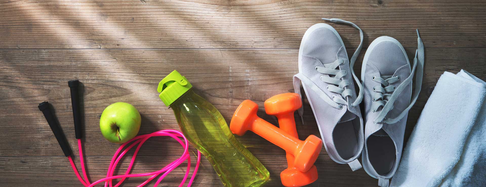Jump rope, apple, water bottle, weights, tennis shoes and towel on the floor