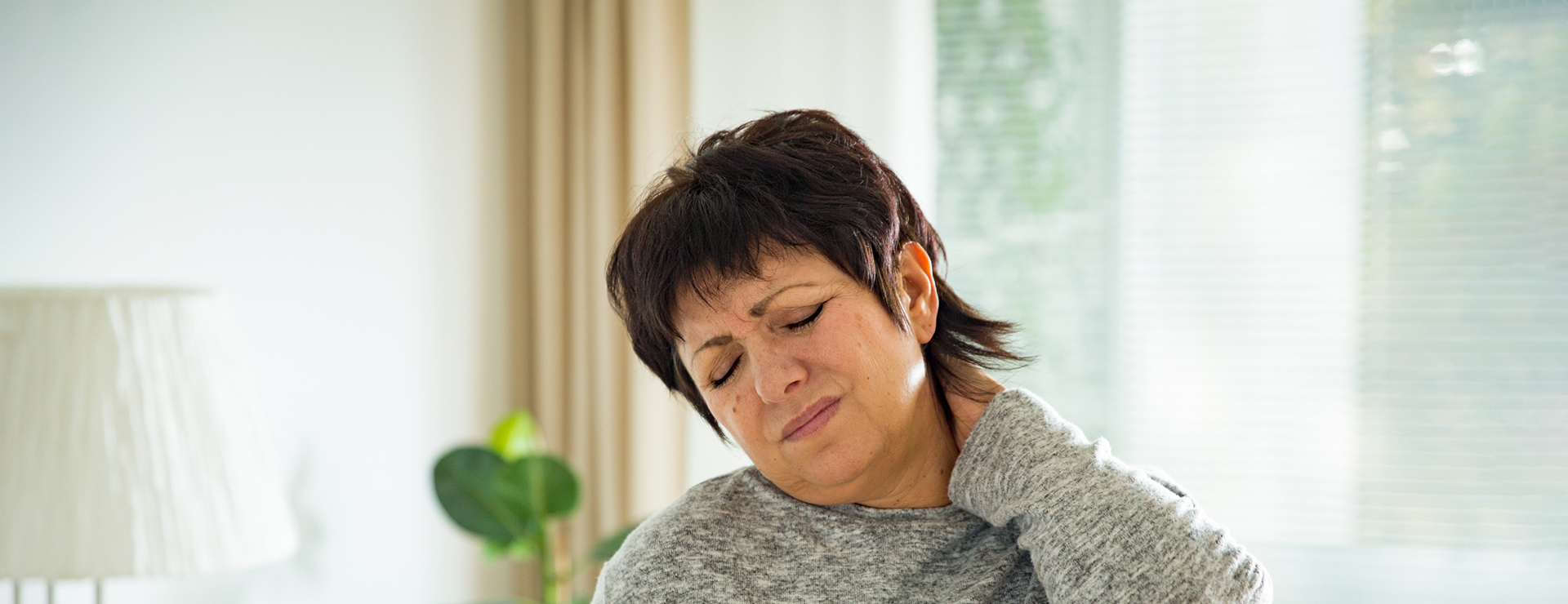 A woman rubs her neck in pain.