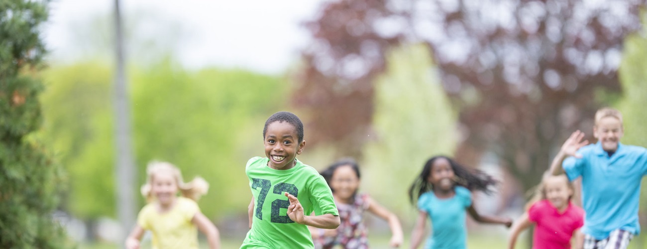 Group of children running outside in the grass