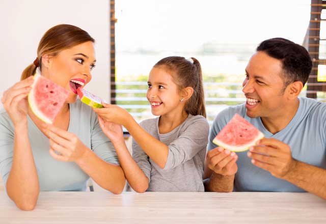 A family eats slices of watermelon together.