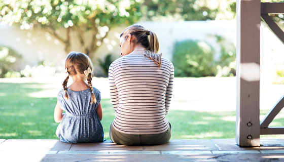 A mother talks to her daughter while sitting on the back porch.