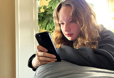 a teen girl uses her phone to research social media and depression